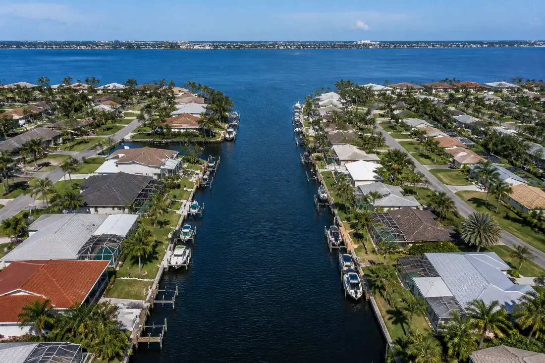 A residential canal meeting a wider waterway at its mouth