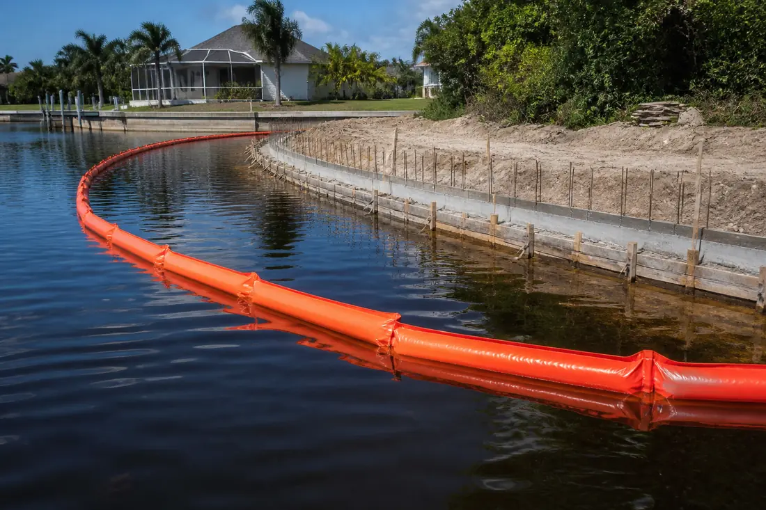 A floating turbidity screen enclosing a seawall construction site on a Cape Coral canal
