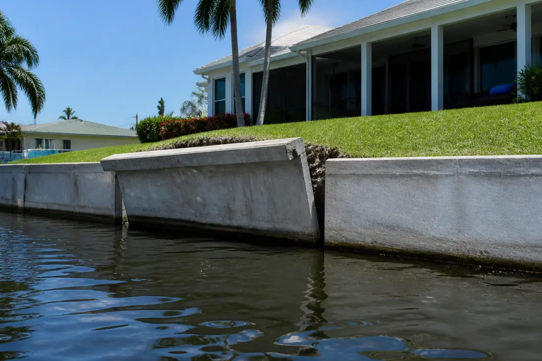 A concrete seawall leaning outward toward the canal along one run